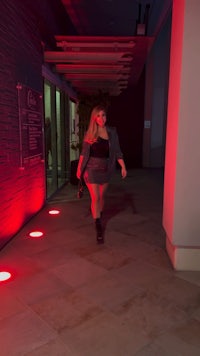 a woman walking down a hallway at night