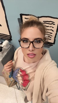 a woman in glasses is taking a selfie in a bathroom